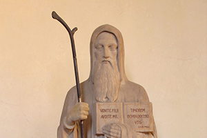 Svatý Benedikt s úryvkem textu ze své Řehole: „Pojďte synové a slyšte mě, naučím vás bát se Hospodina“ (socha v interiéru klášterního kostela).